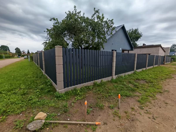 Štaketa žogs uz betona stabiem, pasētām
